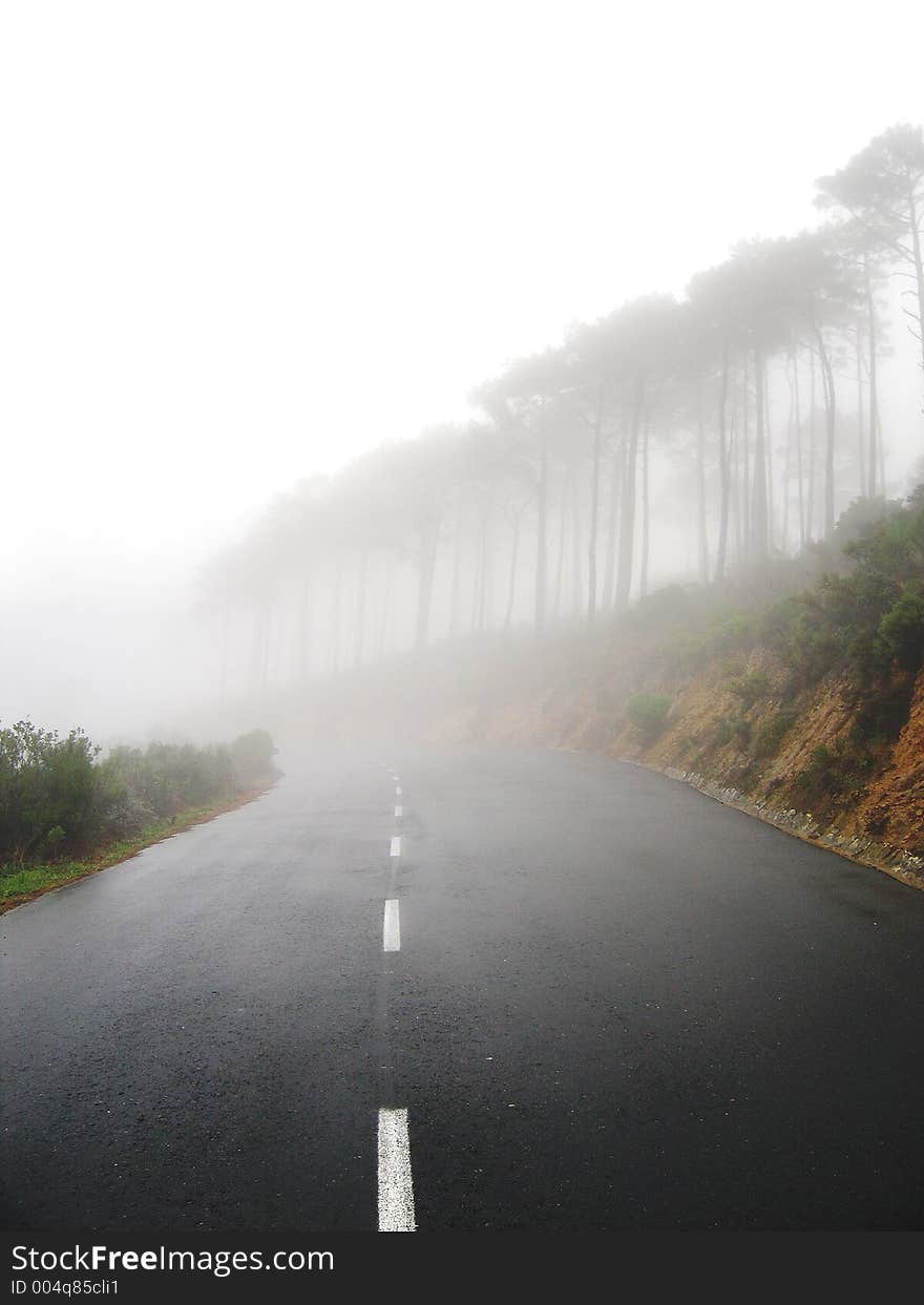 Portrait photo of a mountain slope shrouded in mist with road. Portrait photo of a mountain slope shrouded in mist with road.