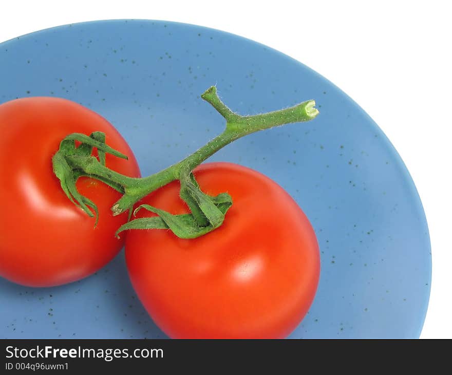 Two red tomatoes on a blue plate on white background