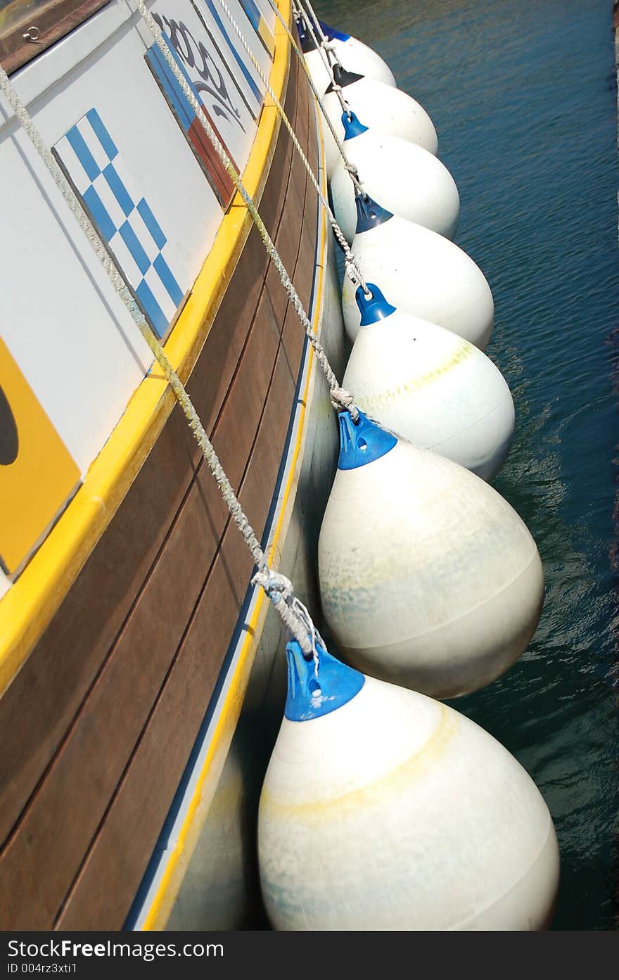 A line of fenders along a touristic ship's board in Syracuse harbor.