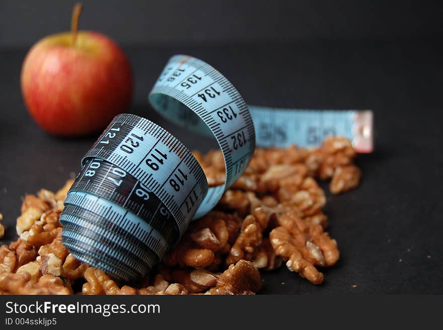 This is an image of a measuring tape, walnuts and an apple. (Please let me know where the image will be used by leaving a message in the Comments Section/See Portfolio). This is an image of a measuring tape, walnuts and an apple. (Please let me know where the image will be used by leaving a message in the Comments Section/See Portfolio)