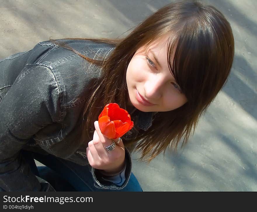 The girl with a flower on a background of asphalt. The girl with a flower on a background of asphalt