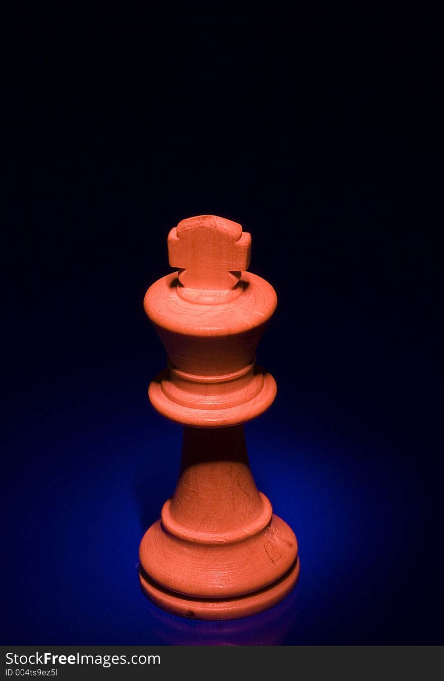 King chess piece with red light from above on blue background. King chess piece with red light from above on blue background