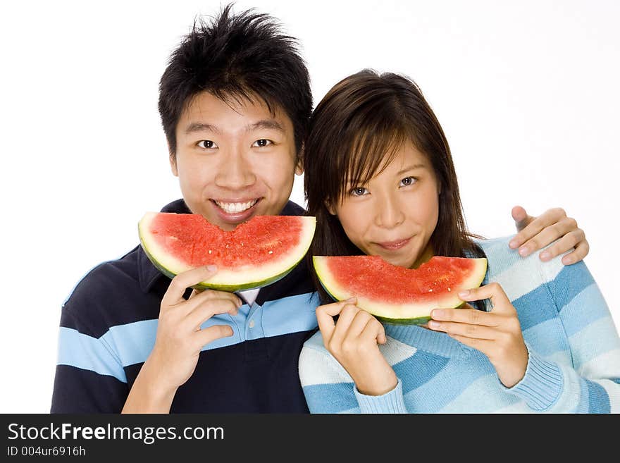 A young asian couple eating watermelon. A young asian couple eating watermelon