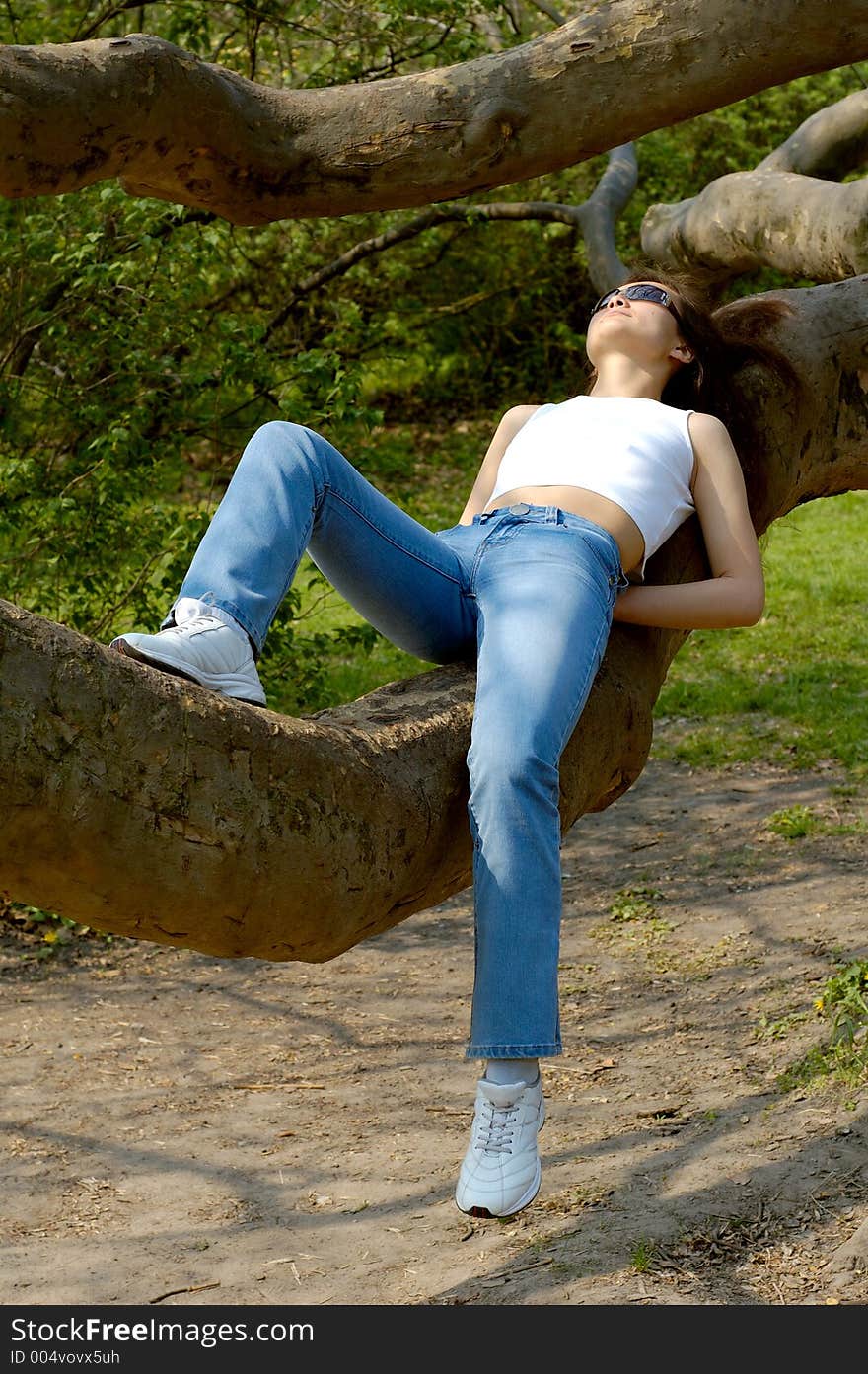 Happy girl relaxing outdoors on tree branch