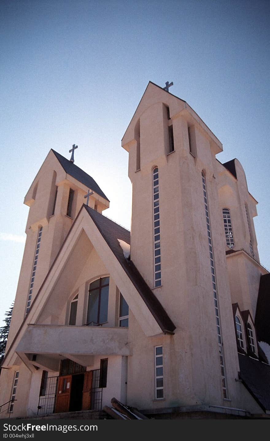 Perspective view of a christian church with tall twin towers, under a deep blue sky. 35mm film scan. Perspective view of a christian church with tall twin towers, under a deep blue sky. 35mm film scan.