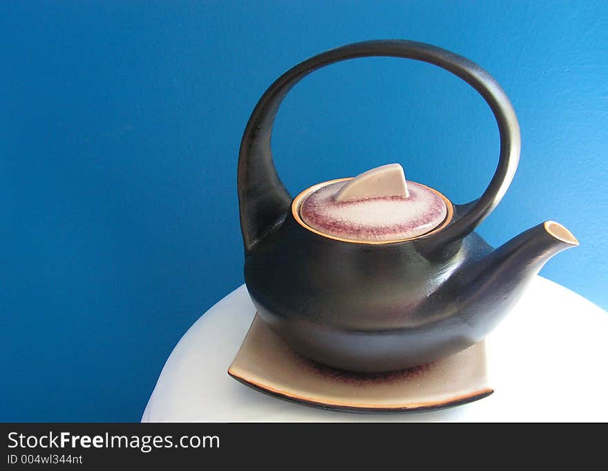 Asian teapot isolated against blue wall