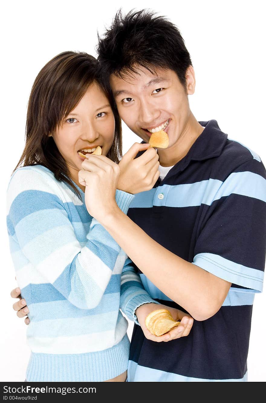 A young couple feeding each other chips. A young couple feeding each other chips