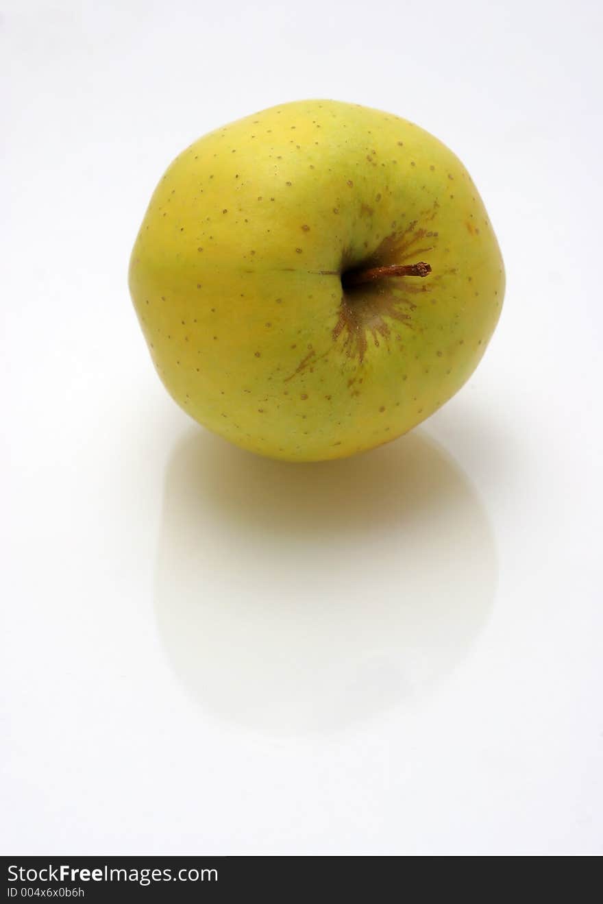 Yellow green apple on reflective surface