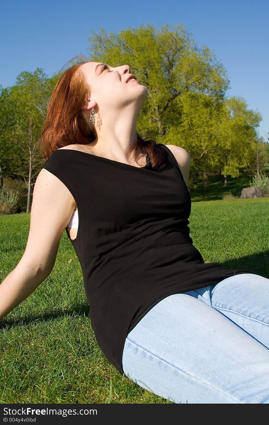 An attractive young woman gazes upward on a warm summer day in the park. An attractive young woman gazes upward on a warm summer day in the park.