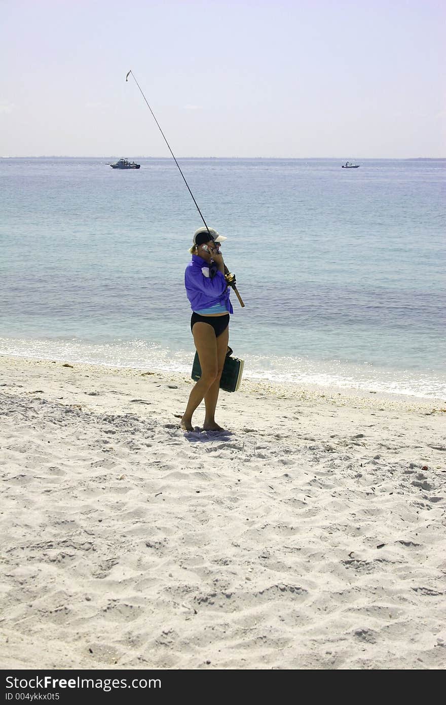 Girl going fishing while talking on her cell phone