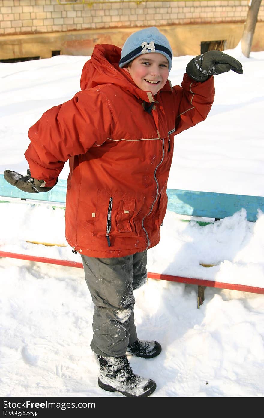 The boy in a court yard dances in the winter in warm clothes