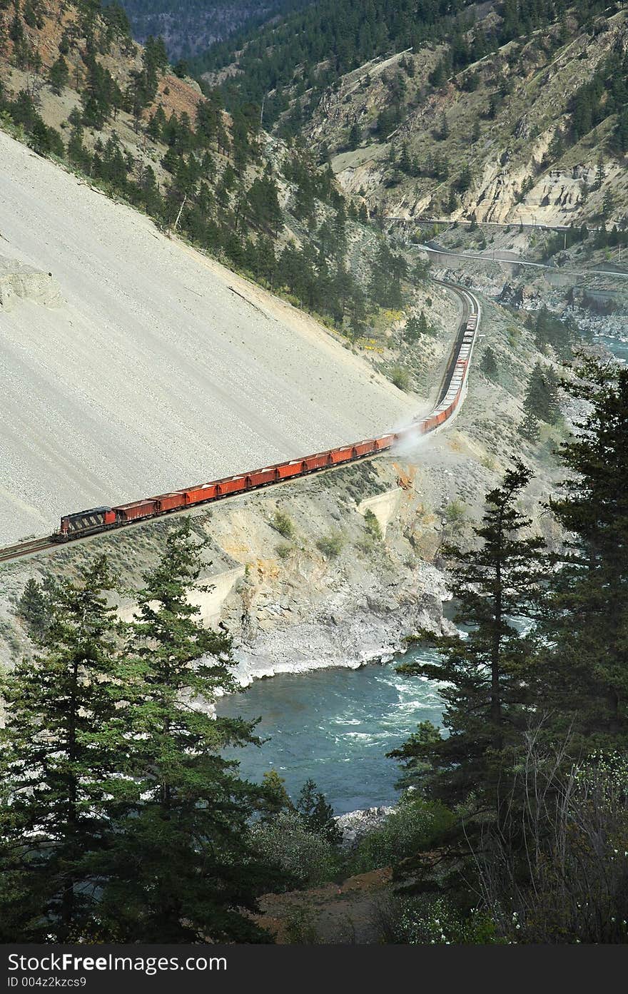 Freight train going through mountain area and near river. BC area