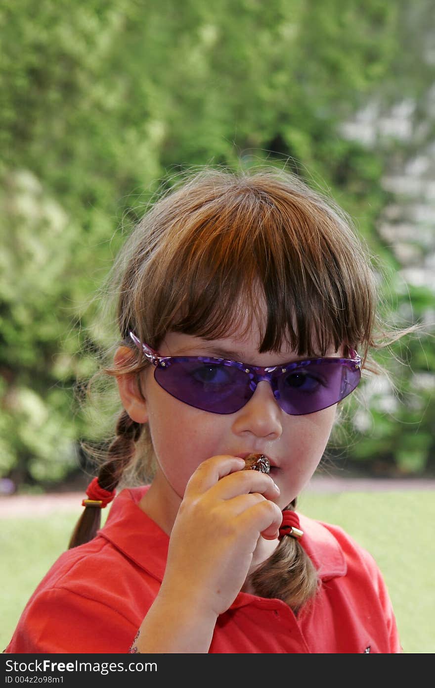 Child with blue sunglasses, eating sweet date