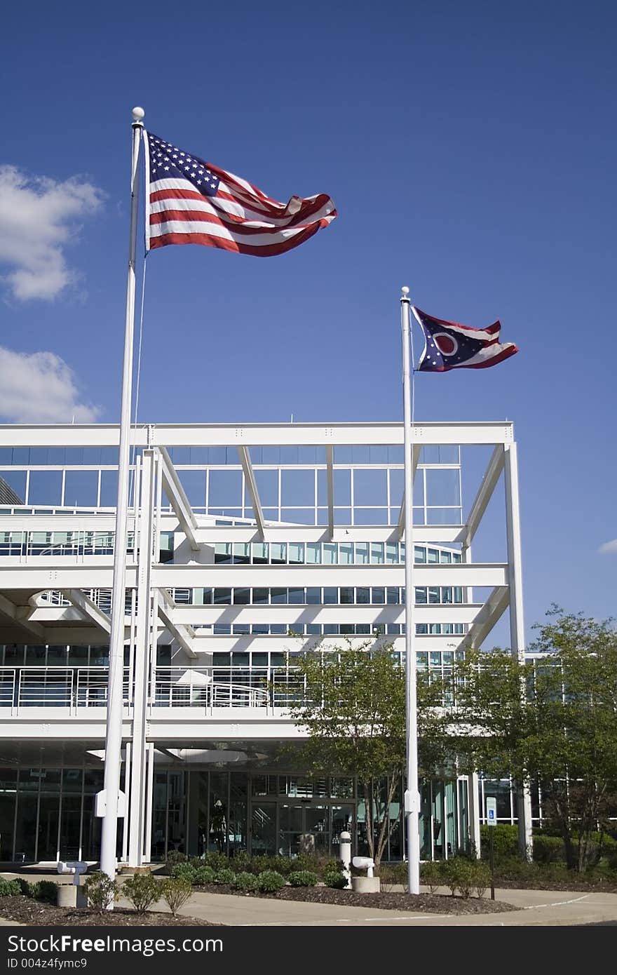 US Flag State of Ohio Flag Front of Modern Building on a bright blue sky.