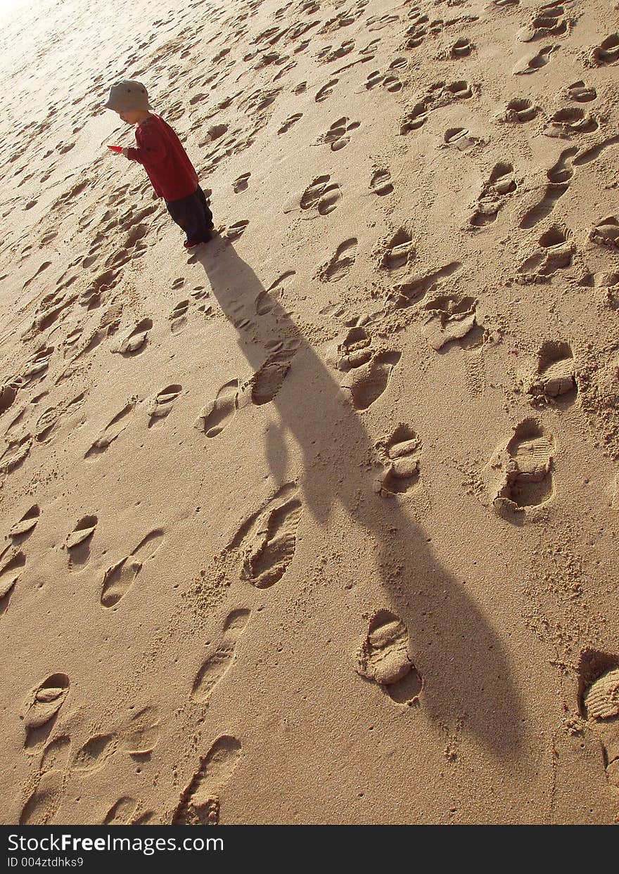 Child standing on a beach surrounded by footprints. Child standing on a beach surrounded by footprints