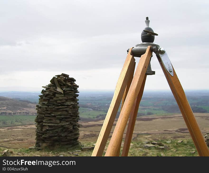 An old tripod next to a cairn on a hilltop. An old tripod next to a cairn on a hilltop