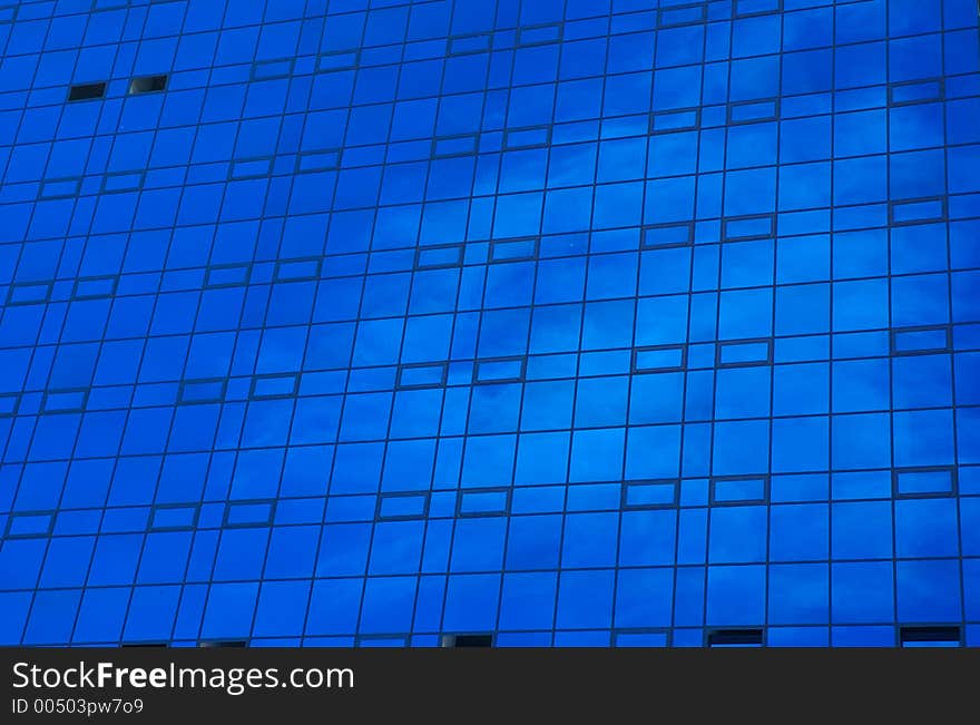 Blue office building with cloud's reflections in windows