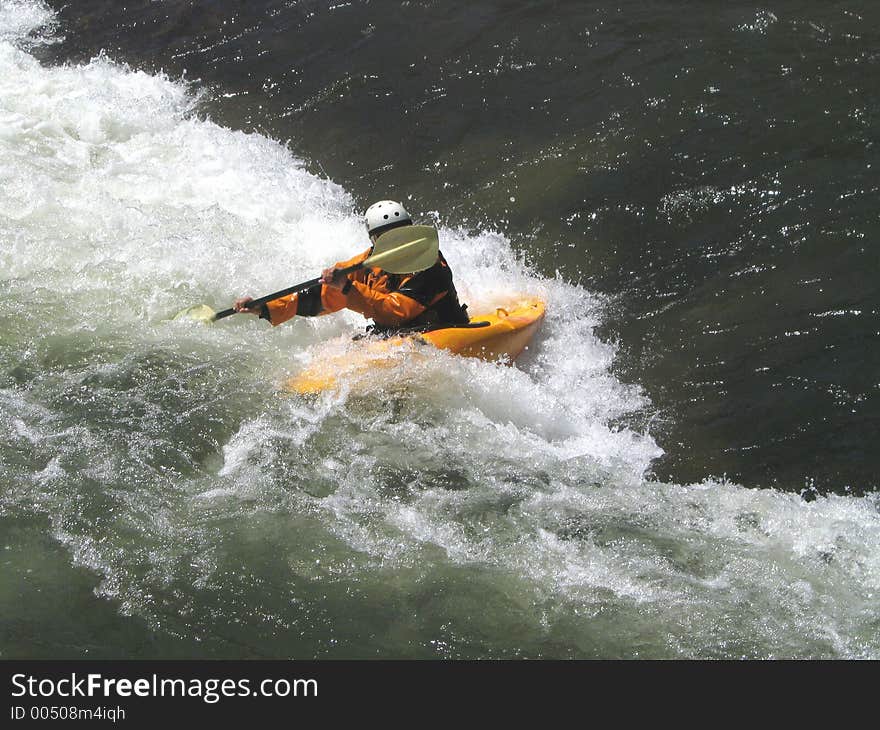 Determined kayaker charging the small rift in the river, forming a frothing, frenzied barrier. Determined kayaker charging the small rift in the river, forming a frothing, frenzied barrier.