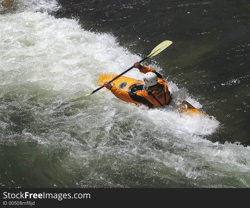 Determined kayaker charging the small rift in the river, forming a frothing, frenzied barrier. Determined kayaker charging the small rift in the river, forming a frothing, frenzied barrier.