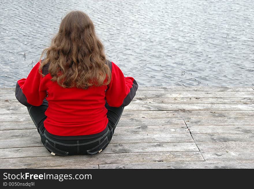 Blonde sitting cross-legged on the jetty. She is lost in meditation. Blonde sitting cross-legged on the jetty. She is lost in meditation.