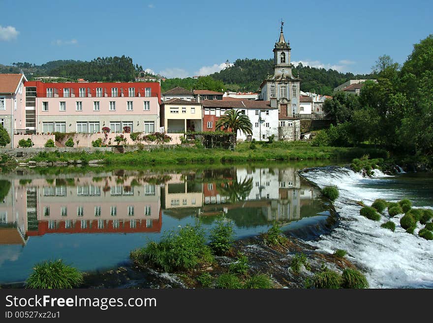 Beautiful village reflected in the river with cascade