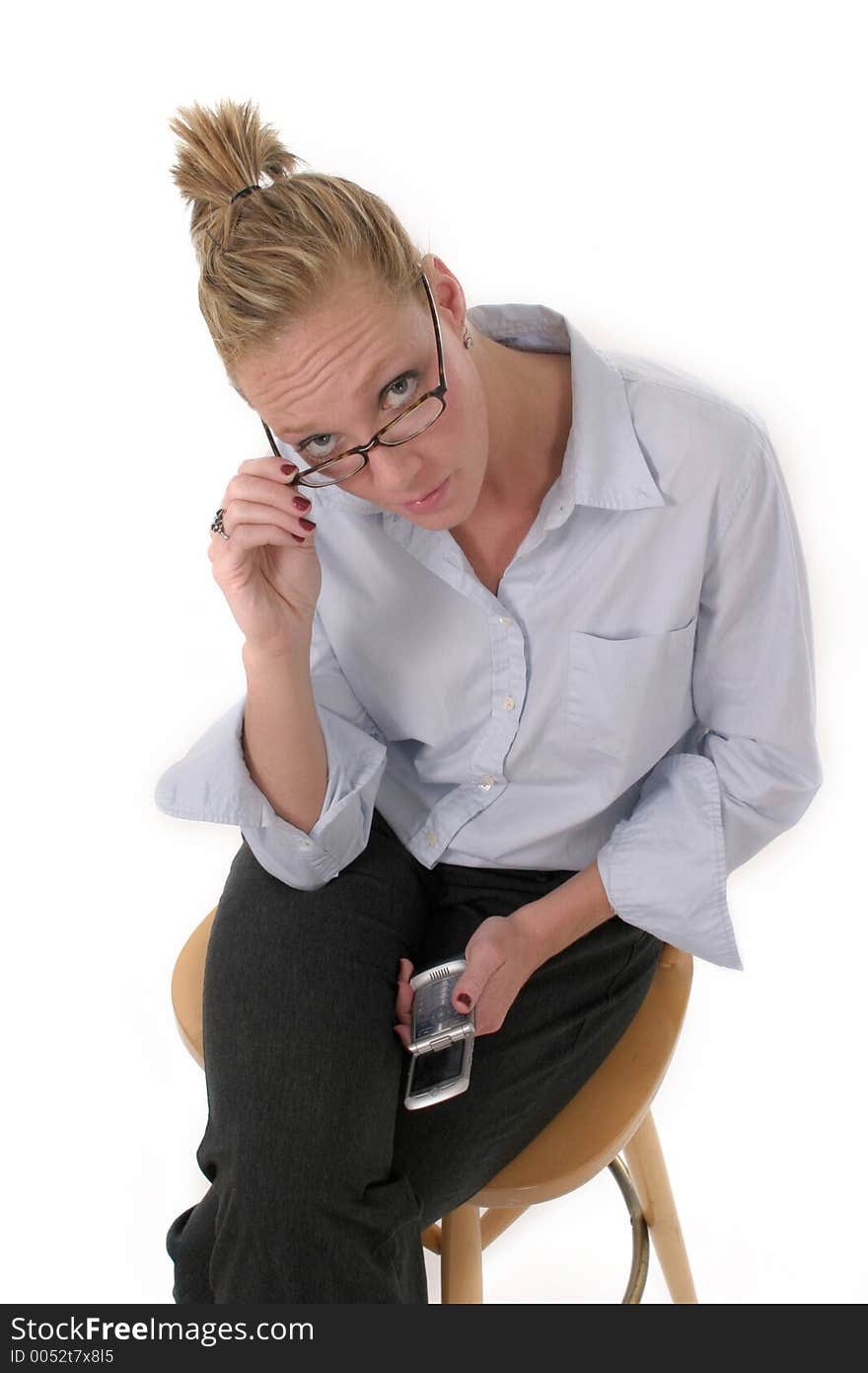 Attractive businesswoman sitting on stool looking over her glasses holding a cellphone. Attractive businesswoman sitting on stool looking over her glasses holding a cellphone