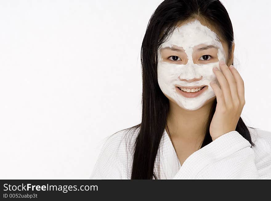 A young asian woman in a bath robe with a face pack on. A young asian woman in a bath robe with a face pack on