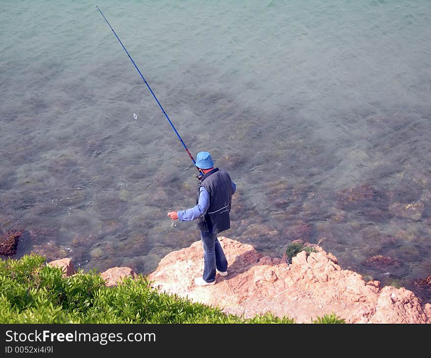 Alone man in blue with a fishing cane. Alone man in blue with a fishing cane