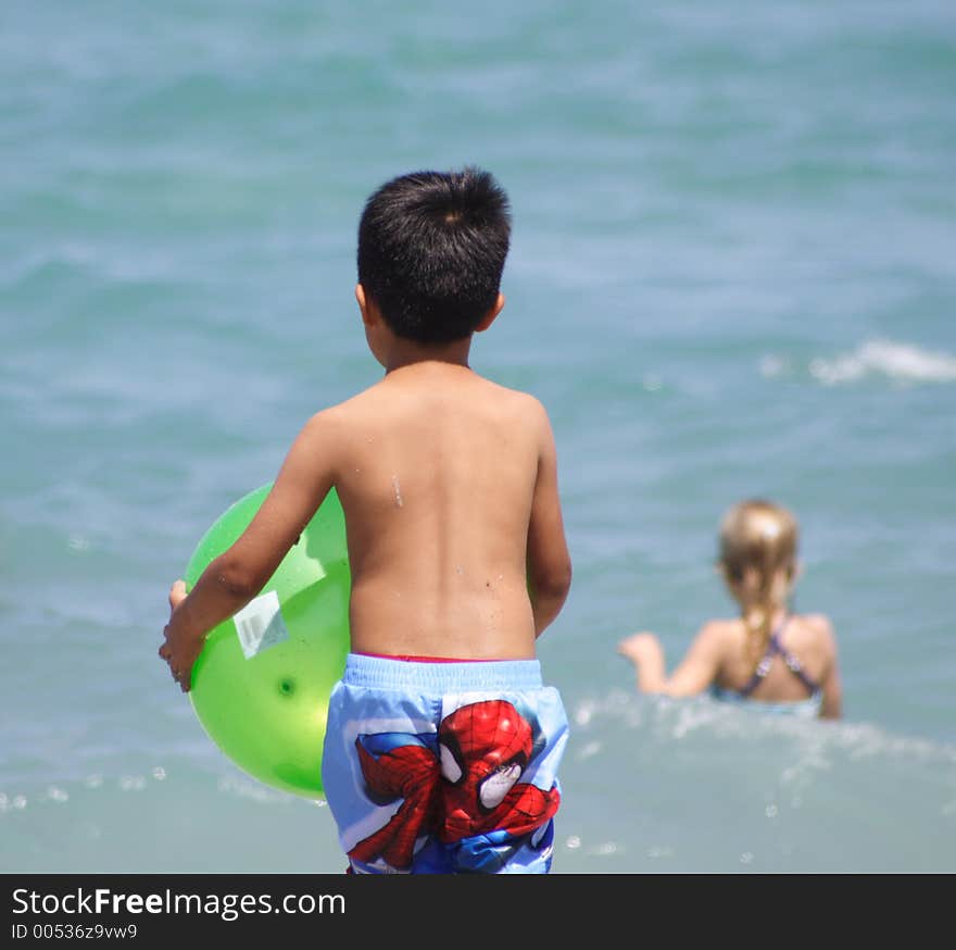 Boy on a beach running into the water with a ball. Boy on a beach running into the water with a ball