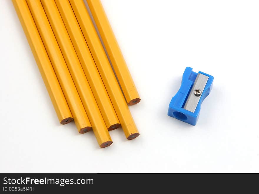 Group of pencils and a sharpener over a white background depicting the situation of sharpening pencils. Group of pencils and a sharpener over a white background depicting the situation of sharpening pencils