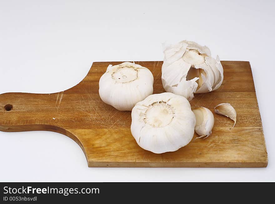 Garlic on a wooden cooking plate, isolated. Garlic on a wooden cooking plate, isolated