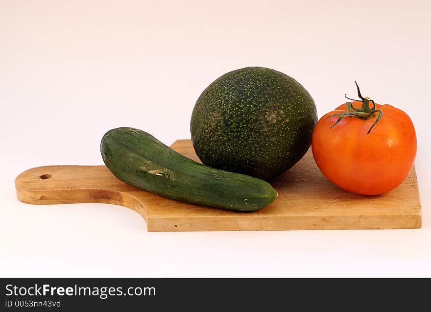 Cucumber, avocado, tomato on a wooden plate. Cucumber, avocado, tomato on a wooden plate