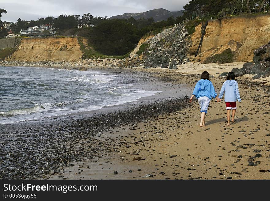 Two young girls walk down the beach.  High Res. Two young girls walk down the beach.  High Res