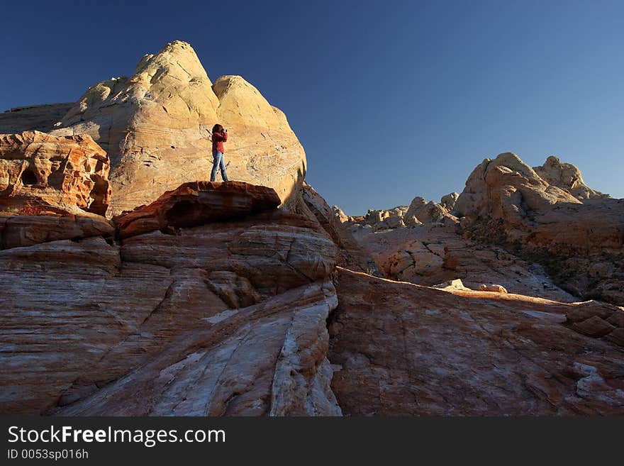 Photographer shooting the Valley of Fire. Early evening lights the rocks behind the photographer. Valley of Fire, Nevada, USA. Photographer shooting the Valley of Fire. Early evening lights the rocks behind the photographer. Valley of Fire, Nevada, USA.