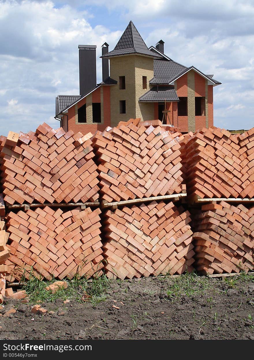 Stacked bricks and built house on the background