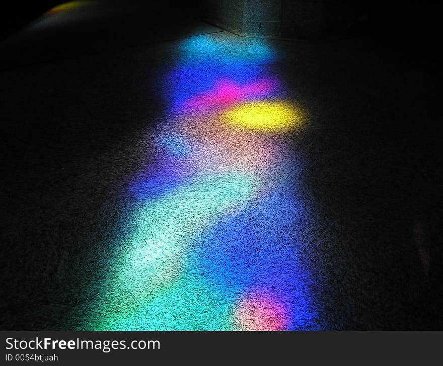 Sunlight falling through a stained-glass window of a church, colouring the floor space. Sunlight falling through a stained-glass window of a church, colouring the floor space.