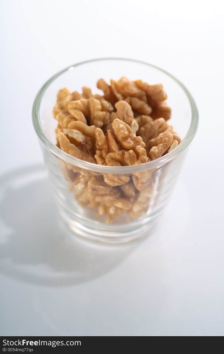 A glass full of crackes walnuts. A glass full of crackes walnuts