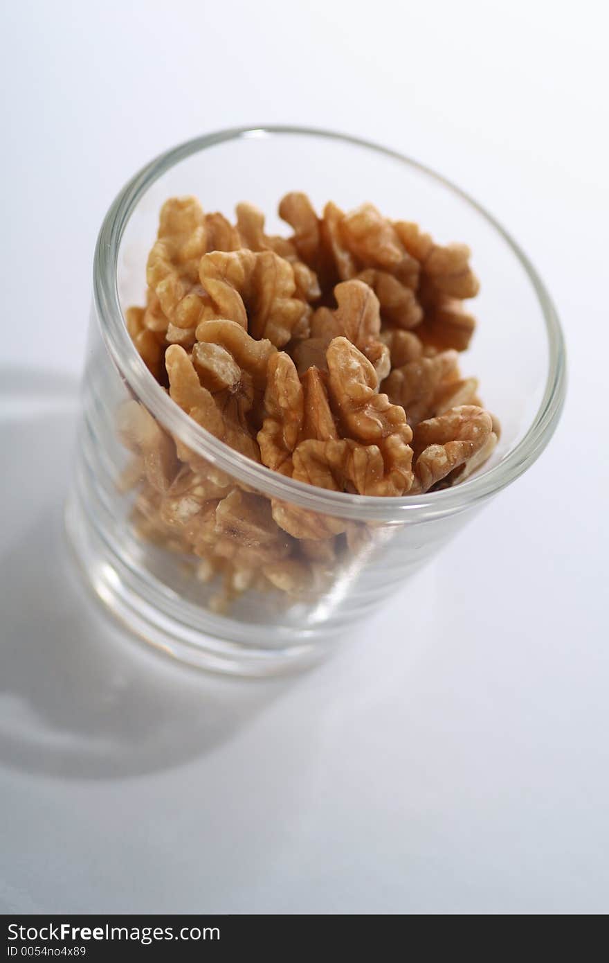 A glass full of crackes walnuts. A glass full of crackes walnuts