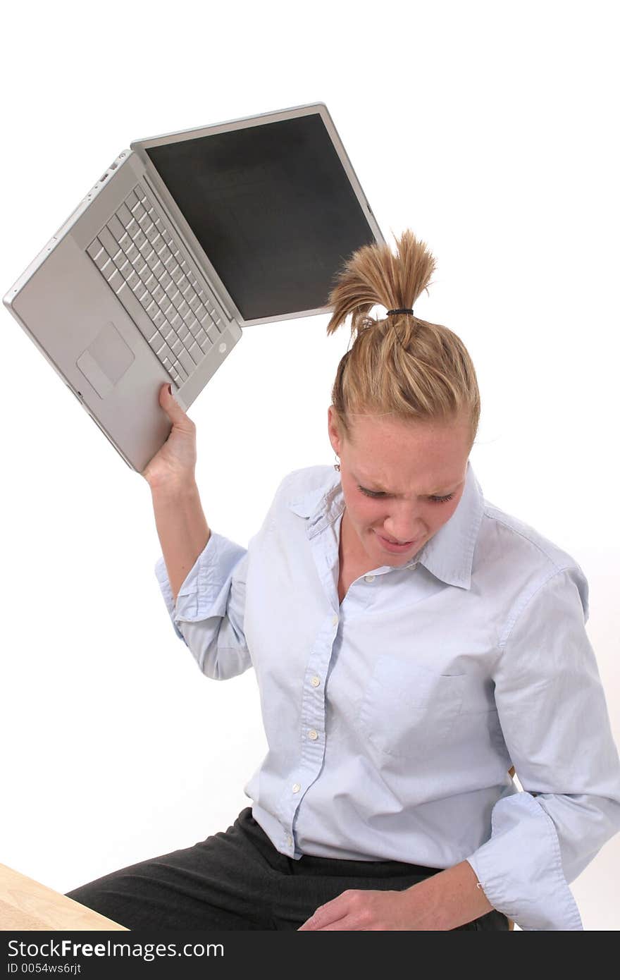 Grimacing and possibly frustrated young business woman seriously considering throwing her laptop computer. Grimacing and possibly frustrated young business woman seriously considering throwing her laptop computer