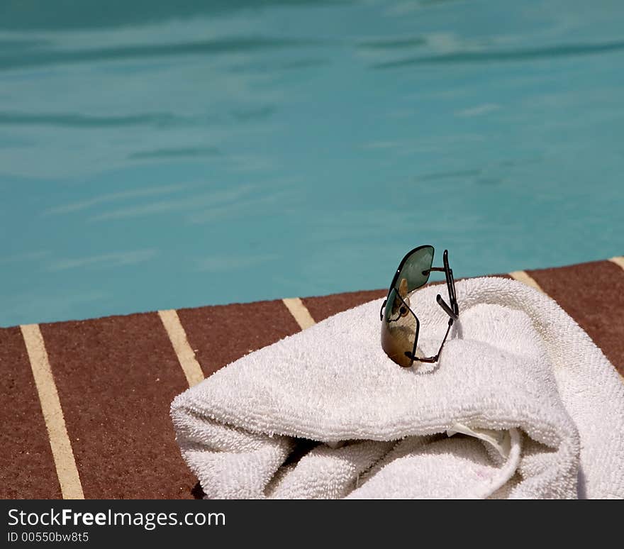 Sun glasses and towel beside a pool. Sun glasses and towel beside a pool