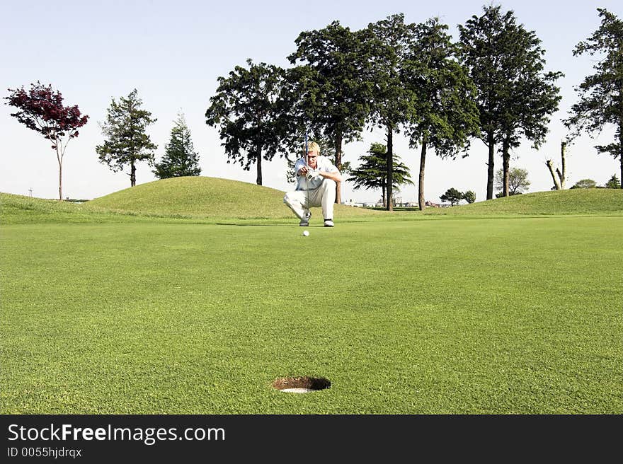 Young male getting a read on the green. Young male getting a read on the green