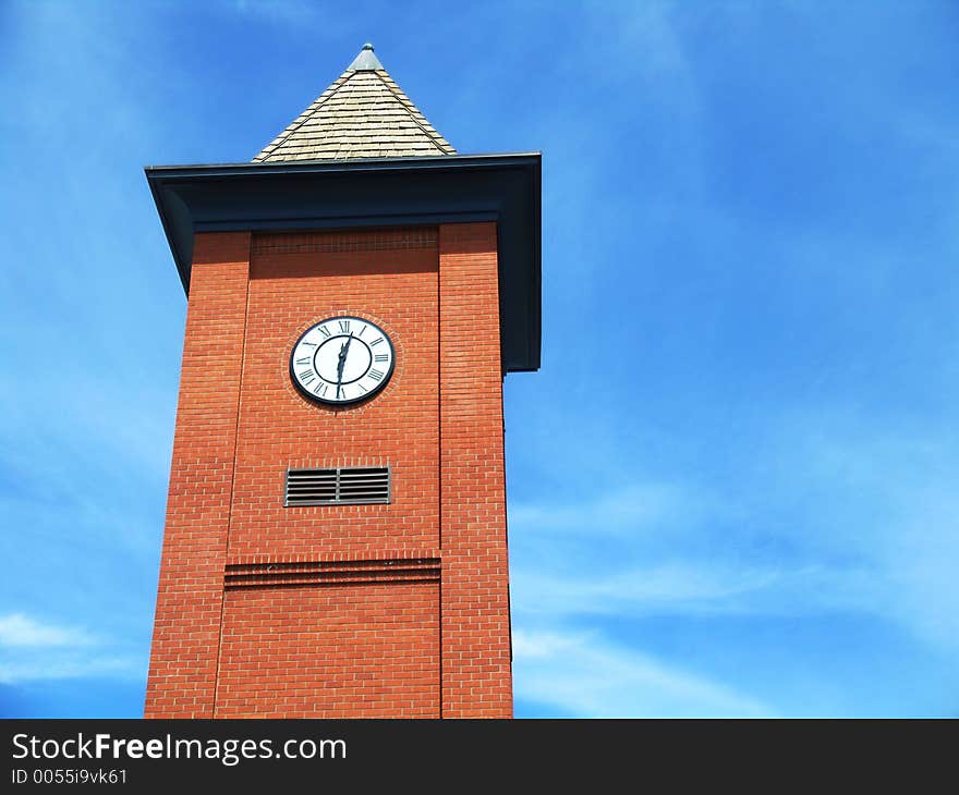 Red brick clock tower with blue sky background