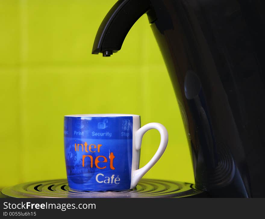 Coffeecup marked with internet and cafe standing on a coffemaker with a bright green background. Coffeecup marked with internet and cafe standing on a coffemaker with a bright green background