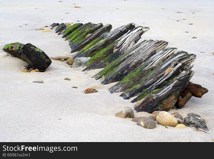 Remains of old wooden fishing boat buried in sand and pebbles. Remains of old wooden fishing boat buried in sand and pebbles.