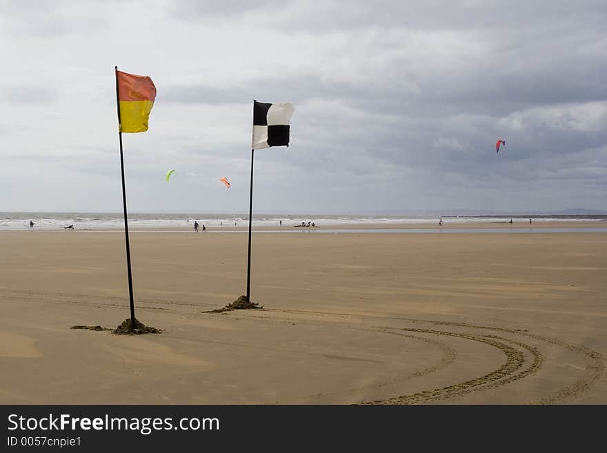 Yellow and red and chequered flags flying on beach. Life savers warning signs. Yellow and red and chequered flags flying on beach. Life savers warning signs.