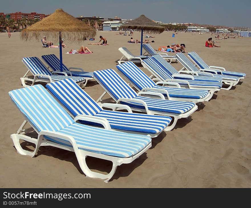 File of eight beach chairs and two umbrellas with two chairs each one behind. File of eight beach chairs and two umbrellas with two chairs each one behind