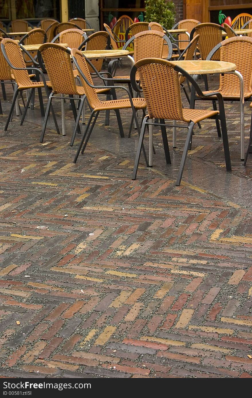 A group of rain soaked chairs sitting on the street. A group of rain soaked chairs sitting on the street