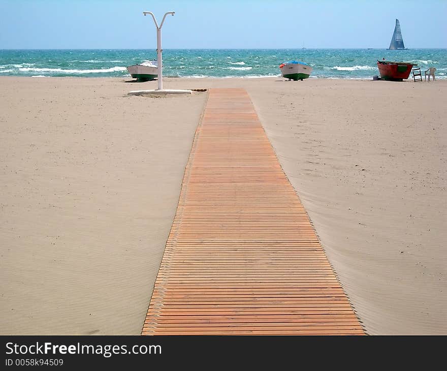 Wooden footbridge in the sand of a beach for access to the sea. Wooden footbridge in the sand of a beach for access to the sea