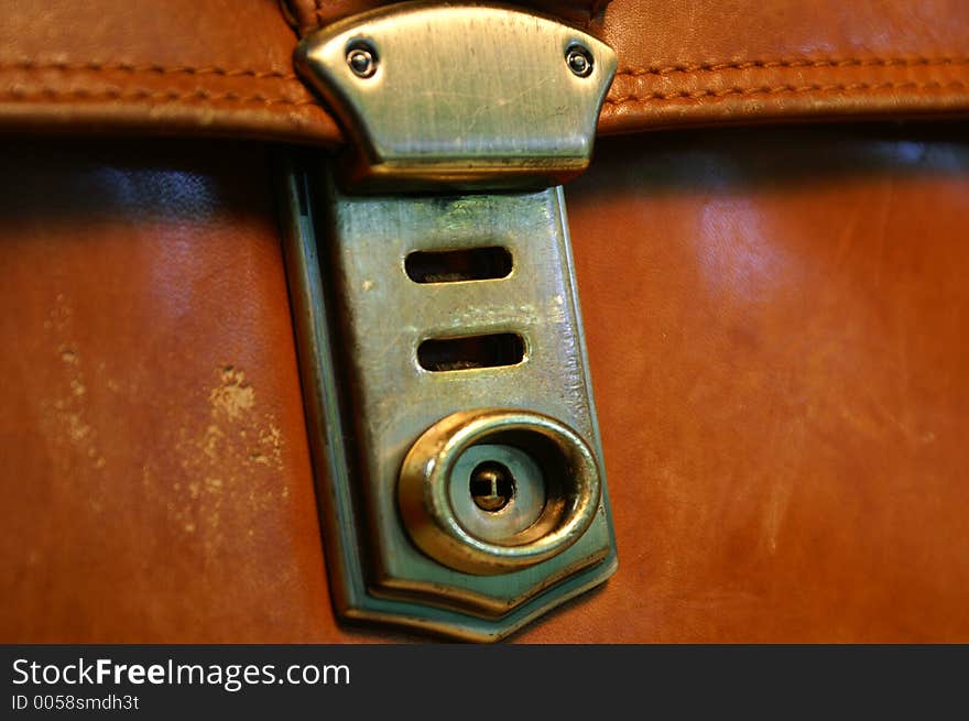 Brassy clasp on brown briefcase. Brassy clasp on brown briefcase