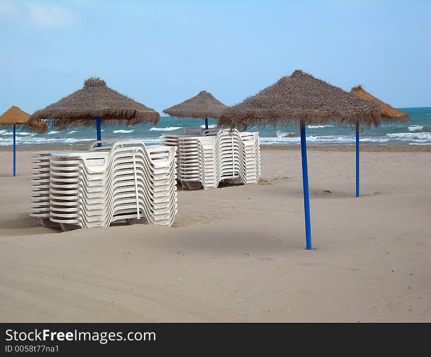 Several piles of chairs and umbrellas in the beach. Several piles of chairs and umbrellas in the beach